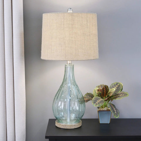 Blue Embossed Glass Table Lamp With Jute Wrapped Base And Tall Silver Finial on a black side table beside a potted plant