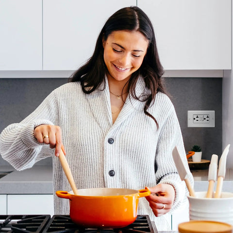 Woman cooking with orange pot near Three Pack GFCI Outlet 20 Amp with LED Indicator, Self-Test, Non-Tamper-Resistant GFCI Duplex