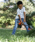 Child playing with 223L Toy Trimmer With Realistic Sounds And Light Up Trimmer Line For Kids Ages 3 And Up A Kid Friendly Weed Eater Play Tool For Budding Gardeners And Little Landscaping Pros Gift Idea outdoors in garden.