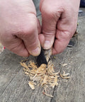 Using Ferro Rod Fire Starter Kit With A Large One Half Inch Rod, Fire Tinder, and Custom Carry Pouch for wood shavings on outdoor table