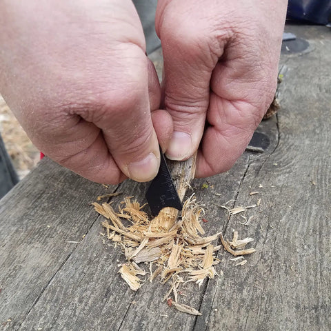 Using Ferro Rod Fire Starter Kit With A Large One Half Inch Rod, Fire Tinder, and Custom Carry Pouch for wood shavings on outdoor table