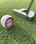 Golf Putting Training Aid With Instant Feedback For Stroke Improvement On Practice Green Or Mat Realistic Ball Feels And Weighs Like A Real Golf Ball Detects Mis Hits And Boosts Accuracy And Confidence next to putter on grass