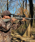 Man aiming a rifle with Springer Air Rifle Scope 3 To 9X40 AO With Illuminated Mil Dot Reticle in a forest setting