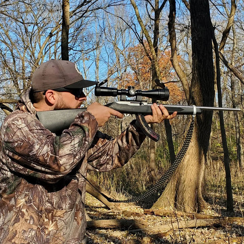 Man aiming a rifle with Springer Air Rifle Scope 3 To 9X40 AO With Illuminated Mil Dot Reticle in a forest setting