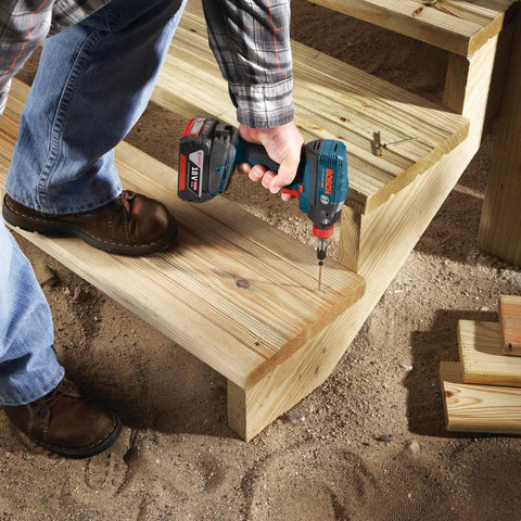 Worker using an impact driver with Impact Tough Phillips Number Two Screwdriving Bits Set, 6 Inch, on wooden stairs.