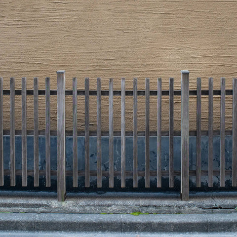 Wooden fence with vertical slats supported by 4x4 posts secured on concrete deck using fence post holder ground spike base anchors