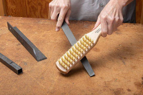 Person using 10 Inch File Card And Brush With Wood Base Grip For Hand Files And Rasps Keeps Teeth Clean And Debris Free Easy Grip Tool For Metalworking And Shop Maintenance