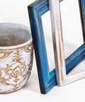 Decorative ceramic planter with white and gold relief pattern; blue and white distressed picture frames.