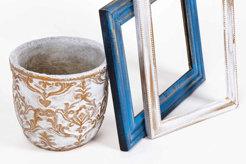 Decorative ceramic planter with white and gold relief pattern; blue and white distressed picture frames.