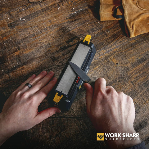 Using Three Sided Benchstone Knife Sharpener With Diamond And Ceramic Abrasives on table, hands holding knife and sharpener.