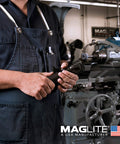 Person in workshop holding 3 Cell D Flashlight With Water Resistant Body, Black Finish, for Outdoors and Emergencies