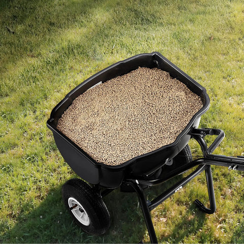 Top view of Walk Behind Broadcast Spreader For Lawn And Garden, 60 Lb Capacity, filled with granules on grass.