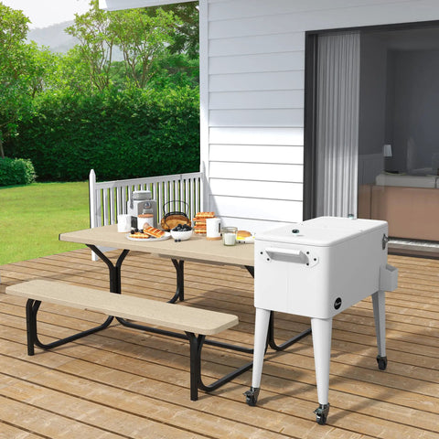 80 Quart Rolling Cooler Cart With Bottle Opener And Drainage On Wheels Portable Patio Beverage Cart For Pool Deck Outdoor Parties And Cookouts White Great For Summer on a patio next to a picnic table.