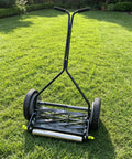 Sleek Stainless Steel Conveyor Rollers 10 Inch Length, 1.5 Inch Diameter, 1/4 Inch Axle on grass with handle and wheels.