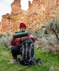 Camper with Medium Duty Ripstop Camping Tarp 6 By 8 Feet Waterproof Cover Dark Green preparing gear in rocky outdoor terrain