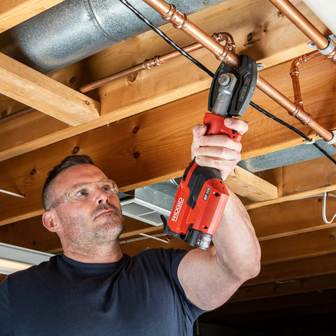 Man using Ultra Lightweight Mini Press Tool Kit With ProPress Jaws For One Half To Three Quarters Inch on copper pipe overhead