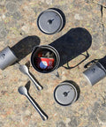 Camping cookware set with Ultralight Titanium Long Spoon For Backpacking And Camping, Durable Camp Utensil, on rocky surface.