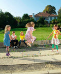 Children playing outdoors with Double Dutch Jump Rope Set 16.4 Ft 2 Pack With Beaded Plastic DIY Segmented Rope, extra handles included.
