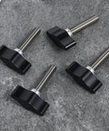 Four Piece Heavy Duty Stainless Steel Wing Knob Set Featuring Quarter Inch Coarse Thread And Rugged Black Grip on a gray surface.
