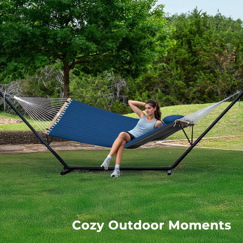 Woman relaxing in a 12Ft Two Person Quilted Outdoor Hammock With Stand Detachable Pillow And Bamboo Spreaders Chill Out Hammock in a backyard