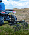 Workhorse Heavy Duty ATV UTV Landscape Rake Tool For Rock, Grass Clumps, And Debris Cleanup attached to ATV on grassy field