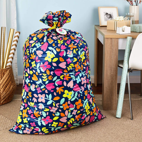 Giant 56 Inch Plastic Gift Bag With Pink And Yellow Floral Print For Large Gifts Like Ottomans, Bedding Sets, Lamps, in room setting