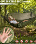 Person relaxing in green Go To Ultra Lightweight Travel Hammock With Pop Up Bug Net For Backpacking And Camping in forest.