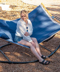 Woman relaxing on Free Standing Outdoor Hammock With Heavy Duty Stand Navy Blue For Backyard Patio And Garden Lounging