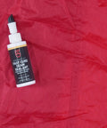 Seam Grip FC Fast Cure Sealant For Tents Rainflies Tarps And Awnings Water Based Seam Sealer 2 Fl Oz bottle on red fabric