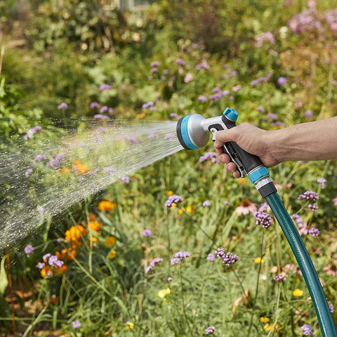 Heavy Duty Front Control Garden Hose Nozzle With 8 Preset Spray Patterns in use watering vibrant garden flowers with ergonomic handle