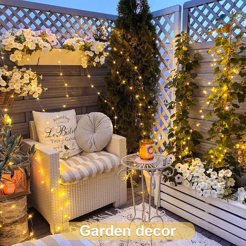 Two Pack Battery Operated Fairy Lights With Remote illuminating outdoor garden corner with chair and floral decor, 132 ft copper wire.