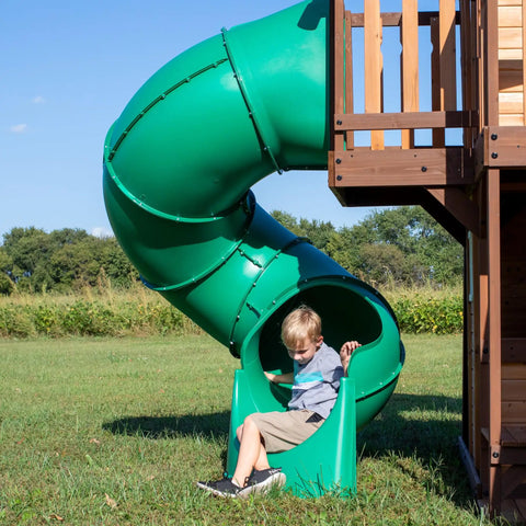 Child playing at the bottom of a spiral tube slide on Cedar Cove Wooden Swing Set With Spiral Tube Slide And Wave Slide