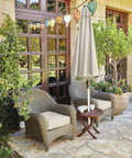 Outdoor seating area with chairs and umbrella on a stone patio, surrounded by plants and decorative glass lights.