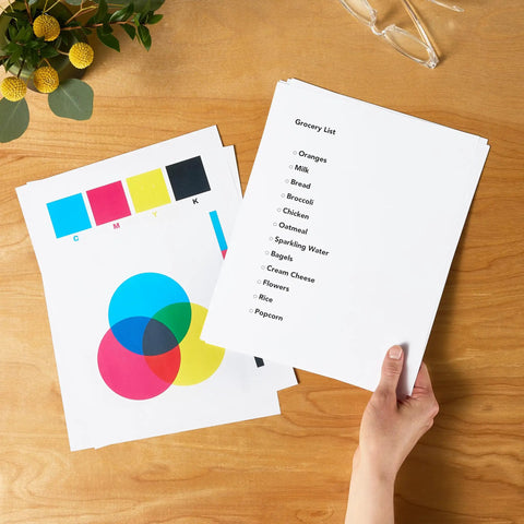 Real Deal Multipurpose Copy Printer Paper 8 Ream Case 4000 Sheets 20 Lb Letter Size 8.5 X 11 Inches on wooden desk with grocery list.