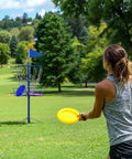 Player aiming at Portable Disc Golf Basket Target With 12 Chains, Sturdy Steel Base, in park setting, blue and yellow theme.