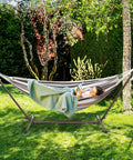 Person relaxing on 550 Lbs Capacity Hammock Stand With Portable Carrying Bag Heavy Duty Two Person Frame For Outdoors And Indoors Black Antique Finish