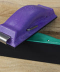 Purple and green ergonomic sanding block on wooden surface, part of the Ergonomic Sanding Block For Wet Or Dry Sanding Easy Load Plain Paper Sander Complete Five Color Code Hand Sanders Set In Yellow Blue Green Purple And Red Time Saver Tool For Quick Grinds