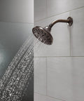 Five Setting Raincan Shower Head With H2Okinetic Spray in Venetian Bronze, showing water flow and wall-mounted installation.
