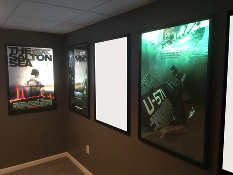 Wall-mounted movie posters with backlit LED panels in a home theater, featuring Two By Four Foot LED Panel Light 50W 6500 Lumen.