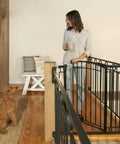 Woman with dog by Multi-Use Tall Walk-Thru Baby Gate In Black Metal, Pressure Mount Or Hardware Mount Options, Adjustable 28 To 48 Inch Wide