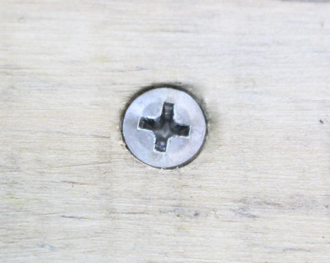 Close-up of Number Twelve By One Inch Stainless Steel Wood Screws Flat Head Phillips Drive embedded in wood.