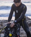Diver wearing Galileo 3 Ti Wrist Dive Computer With Ultra Lightweight Titanium Case on wrist, preparing dive gear on rocky shore.