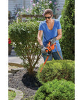 Person using Powerful 3.0 Amp Electric Hedge Trimmer With 16 Inch Blade Lightweight Compact Corded Yard Tool For Quick Clean Shrub Shaping And Pruning Includes Cord Retention outdoors.