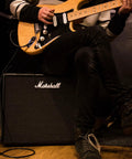 Person playing electric guitar with Marshall amp similar to Code50 Digital Guitar Amplifier With Fifty Watt Output One Hundred Plus Presets Twenty Four Digital Effects Fourteen Preamp Models Bluetooth Connectivity Three Point Five Millimeter Aux Input Versatile Tone For Practice Rehearsal And Live