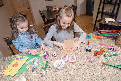 Children using premium natural wood craft sticks for DIY arts and crafts projects at home, surrounded by colorful materials.