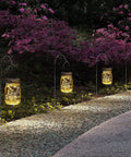 Hanging Mason Jar Solar Lights 6 Pack With 30 LED Lanterns illuminating a garden path at night, jars hanging from hooks