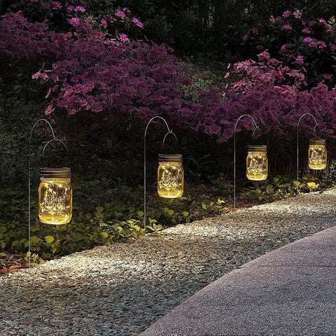 Hanging Mason Jar Solar Lights 6 Pack With 30 LED Lanterns illuminating a garden path at night, jars hanging from hooks