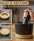 Hand using Mortar And Pestle Set Heavy Duty Granite Stone Grinder With Stable Bamboo Base Extra Long Pestle And Cleaning Brush Perfect For Guacamole Bowl Herb Grinding And Molcajete Bowl One Point Five Cup
