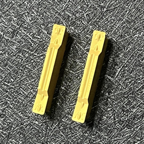 MGMN300-M Coated Carbide Inserts for CNC Lathe Grooving and Steel Cutting, showing two yellow inserts on textured surface