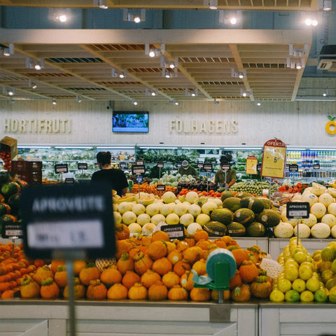 View of a grocery store produce section with assorted fruits and vegetables under LED lighting.